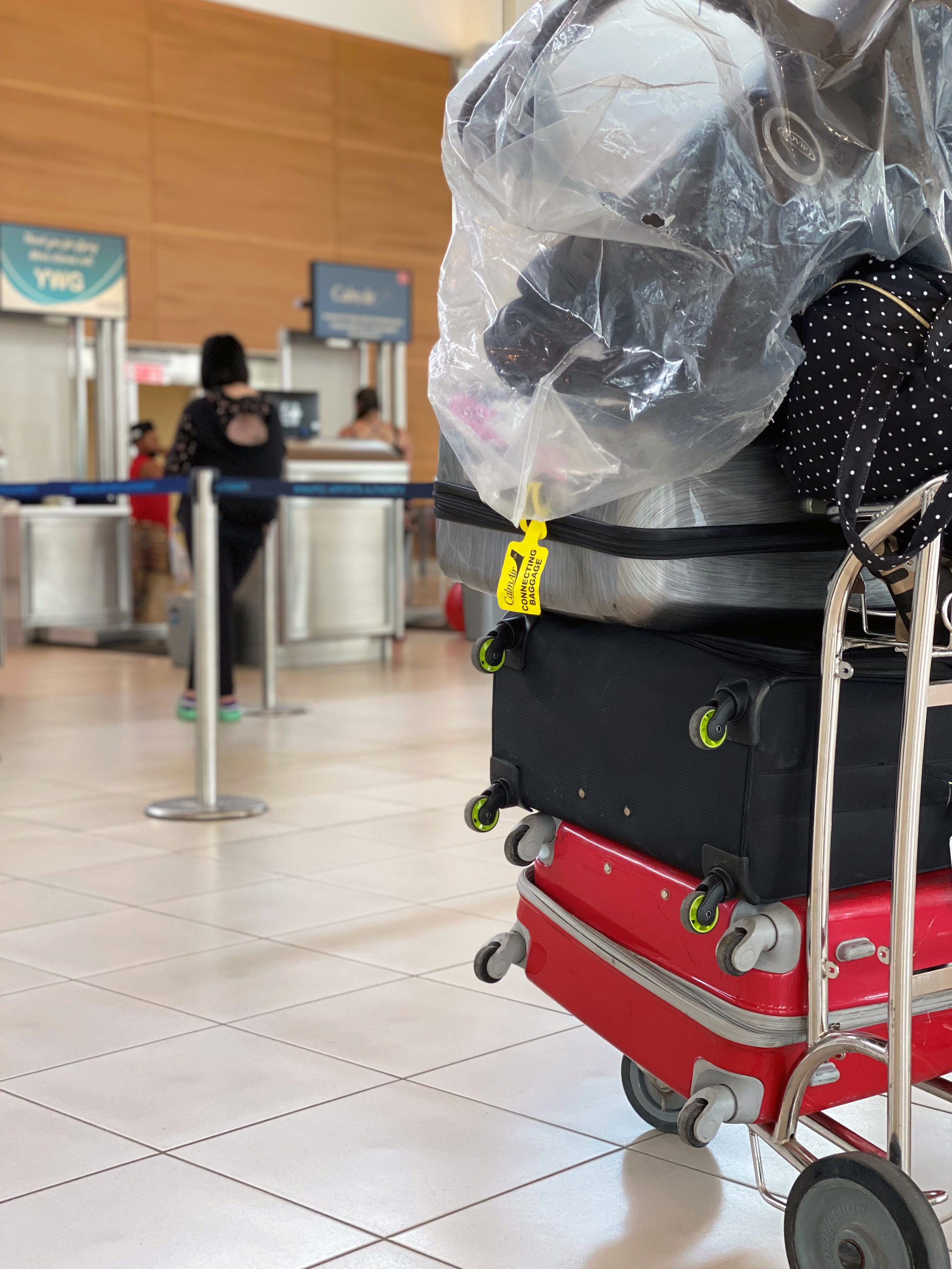 Bags are piled on a luggage cart in front of the Calm Air check-in counters at Winnipeg Richardson International Airport.