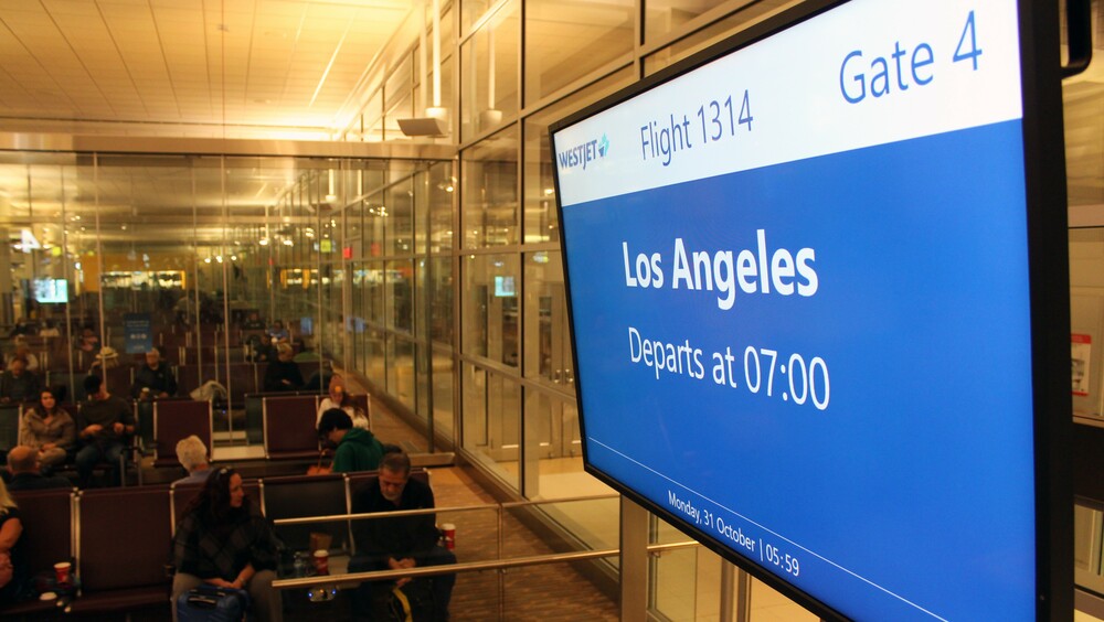 Los Angeles is shown on the flight information screen above the Gate 4 check-in counter at Winnipeg Richardson International Airport.