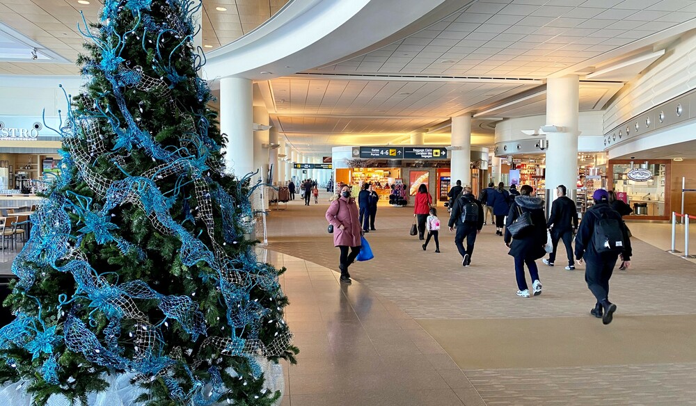 Travellers walk past a festively decorated tree in the domestic and international boarding gate area of Winnipeg Richardson International Airport.